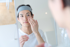 Person applying facial moisturizer to their cheeks.